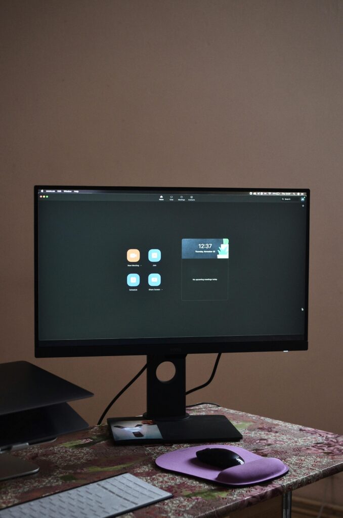 A sleek desktop setup featuring a monitor, keyboard, and mouse on a patterned tablecloth.
