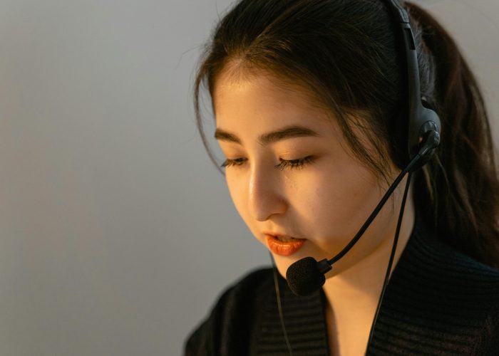 Focused young woman in headset working in customer support, speaking attentively.